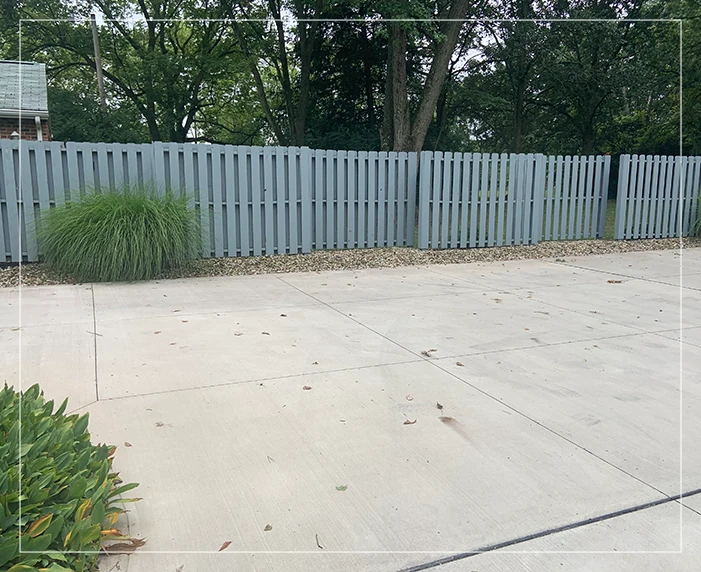 A view of a backyard with a fence and grass.